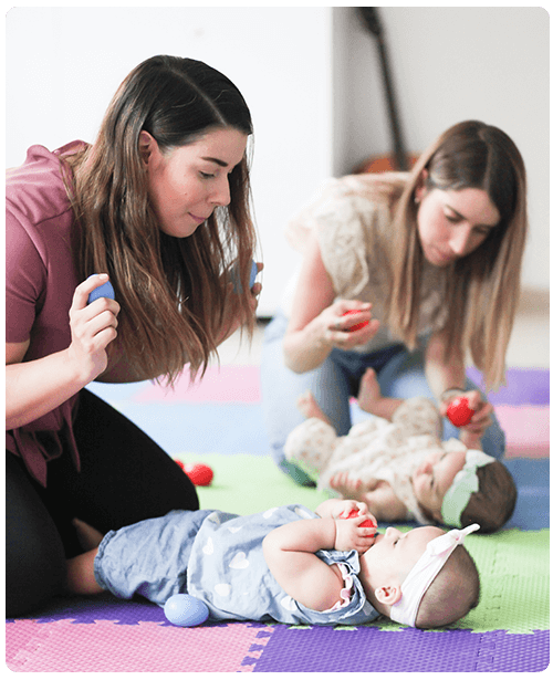 moms with egg shakers singing to babies on floor