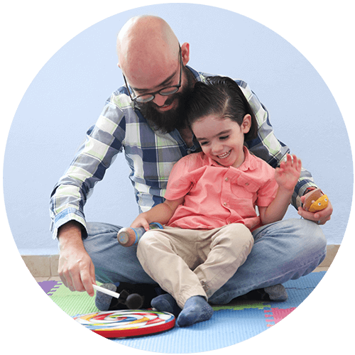 child and father sitting playing drum together