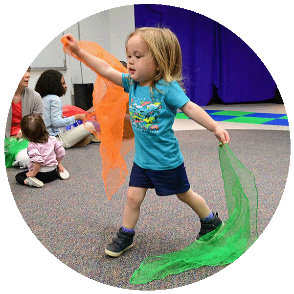 child with scarves in both hands dancing