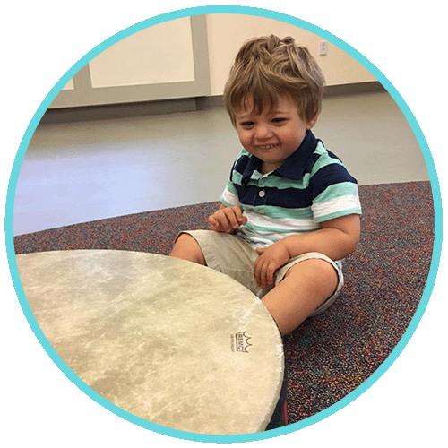 Max as toddler, sitting in front of floor drum