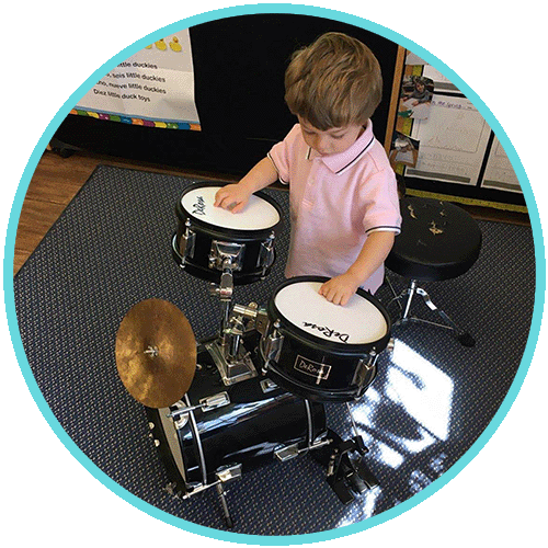 Max playing small drumset in preschool classroom